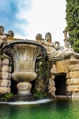 3 Haziran 2016 - Caprarola, Viterbo, Lazio, İtalya - Villa Farnese. Villanın (park) bahçesi. Her iki tarafında sakallı adam heykelleri ve büyük bir vazo bulunan çeşme. Su damlaları.