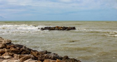 Yağmurlu bir kış gününde dalgalı ve bulanık bir deniz. Bulutlu mavi gökyüzü.