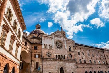 Foligno meydanındaki San Feliciano Katedrali. Yan cephede, 3 tane rozet, camlar, kemerler ve kolonlar. Çan kulesi, kubbe ve ahşap kapı. Perugia, Umbria, İtalya.