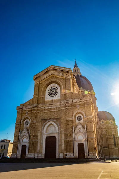 Cathedral of St. Peter the Apostle, also known as Duomo Tonti, by Paolo Tonti. Facade, rose windows, portals, dome and apse. The blinding glare of the sun behind the building. Cerignola, Puglia, Italy.