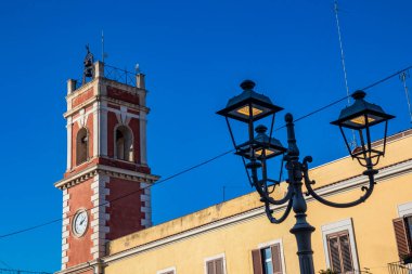 Saat kulesi, beyaz tuğlalı kırmızı. Bina 19. yüzyıla dayanıyor. Demir sokak lambası özgürlük tarzında. Cerignola, Puglia, İtalya.