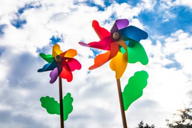 Ahşap çubuklu renkli bir Catherine tekerlek rüzgarı. Aşağıdan çekilen mavi gökyüzü ve arka planda bulutlar, rüzgarlı bir günde.