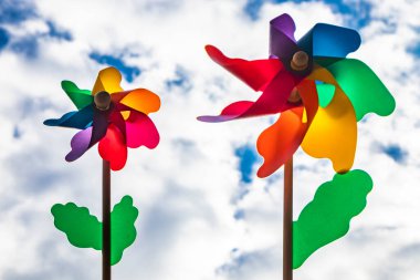 Ahşap çubuklu renkli bir Catherine tekerlek rüzgarı. Aşağıdan çekilen mavi gökyüzü ve arka planda bulutlar, rüzgarlı bir günde.