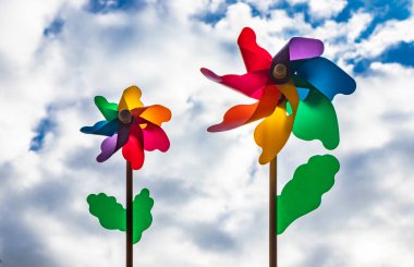 Ahşap çubuklu renkli bir Catherine tekerlek rüzgarı. Aşağıdan çekilen mavi gökyüzü ve arka planda bulutlar, rüzgarlı bir günde.