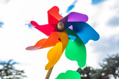 Ahşap çubuklu renkli bir Catherine tekerlek rüzgarı. Aşağıdan çekilen mavi gökyüzü ve arka planda bulutlar, rüzgarlı bir günde.