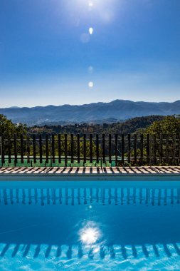 Yazın, sabah güneşiyle dağlarda inanılmaz bir yüzme havuzu. Rahatlama, tatil, lüks, dinlenme, tatil, boş zaman kavramı. Fenerli ve ışıltılı bir sahne..