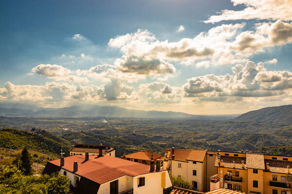 Bellegra, Rome, Lazio, Italy - The panorama seen from Bellegra, with the Prenestini mountains and the Sacco Valley. The cloudy blue sky at sunset. The roofs of houses. Mountains and sunbeams.