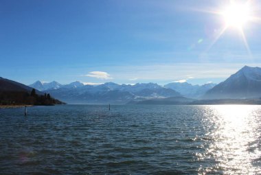 Kışın karla kaplı dağların arasında göl manzarası. Thun Gölü İsviçre 'nin Bern kantonunda bulunan bir göldür. Aare nehri tarafından oluşturulan doğal bir göldür..