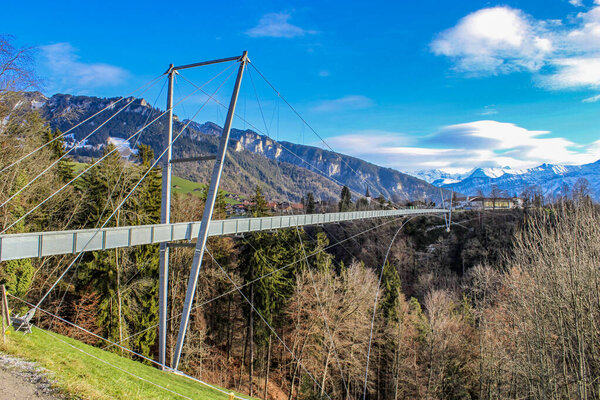 впечатляющий подвесной мост (пешеходный), в железе, в муниципалитете Зигрисвиль, в районе Тун в кантоне Берн, Швейцария. Вид на горы и озеро зимой
.