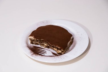 Beyaz arka planda izole edilmiş beyaz seramik tabakta ev yapımı tiramisu. Geleneksel İtalyan tatlısı, kakao, kahve, mascarpone ve bisküvi.. 