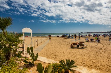 14 Haziran 2019 - Nettuno, Lazio, Roma, İtalya - Yazın sonlarında rüzgarlı bir günde, kapalı şemsiyeler ve yarı ıssız bir plaj. Bulutlu mavi gökyüzü. Hiç kimse, hiç kimse.