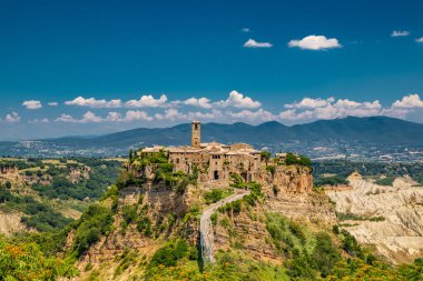 View of the medieval town of Civita di Bagnoregio, located on the top of a spur of tuff rock, in the middle of the valley of the badlands. Connected to the city by a small bridge, mule track.  clipart