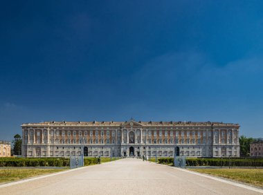 3 Temmuz 2020 - Caserta Kraliyet Sarayı - Büyük caddesi ve ana girişi olan görkemli sarayın cephesi. Birçok pencere, sütun ve mermer süslemeler. Yazın mavi gökyüzü