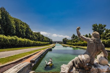 3 Temmuz 2020 - Caserta Kraliyet Sarayı - Parkın yapay gölünün çok uzun havzası. Bakış açısı. Mermer heykeller bakar ve ellerini saraya doğru uzatırlar. Mavi gökyüzü