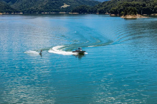 The lake of Salto, the largest artificial lake in Lazio, in the province of Rieti and created by damming the Salto river with the Salto dam. A sportsman practices water skiing towed by a motorboat.