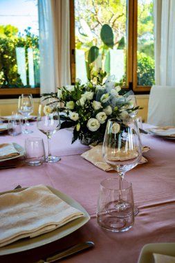 Bir İtalyan restoranında tören için masa hazır. Bir düğün için kutlama var. Şampanya dolu bir sepet. Çiçek süslemeleri. Pembe masa örtüsü. Lüks, zarafet, zarafet..