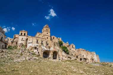 Craco, Basilicata, İtalya. Bir heyelan sonucu hayalet kasaba yok edildi ve terk edildi. Çökmüş evler ve bitkiler tarafından istila edilmiş kalıntılar. Kırık duvarlar, pencereler ve kapılar. Kilisenin çan kulesi.