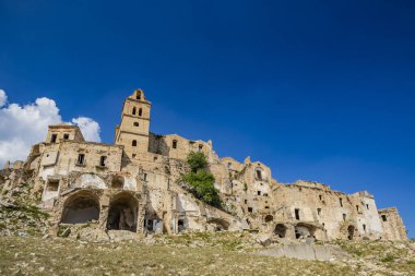 Craco, Basilicata, İtalya. Bir heyelan sonucu hayalet kasaba yok edildi ve terk edildi. Çökmüş evler ve bitkiler tarafından istila edilmiş kalıntılar. Kırık duvarlar, pencereler ve kapılar. Kilisenin çan kulesi.
