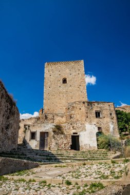Craco, Matera, Basilicata, İtalya. Hayalet kasaba bir heyelan tarafından yok edildi. Çökmüş evler ve bitkiler tarafından istila edilmiş kalıntılar. Eski gözetleme kulesi hala ayakta şehre bakıyor..