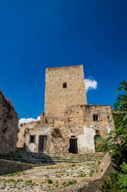 Craco, Matera, Basilicata, İtalya. Hayalet kasaba bir heyelan tarafından yok edildi. Çökmüş evler ve bitkiler tarafından istila edilmiş kalıntılar. Eski gözetleme kulesi hala ayakta şehre bakıyor..