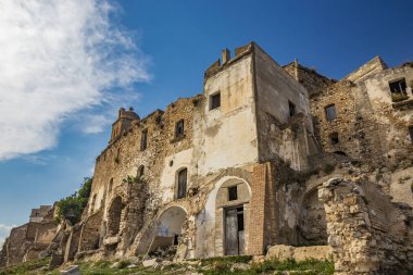 Craco, Basilicata, İtalya. Bir heyelan sonucu hayalet kasaba yok edildi ve terk edildi. Çökmüş evler ve bitkiler tarafından istila edilmiş kalıntılar. Kırık duvarlar, pencereler ve kapılar. Kilisenin çan kulesi.