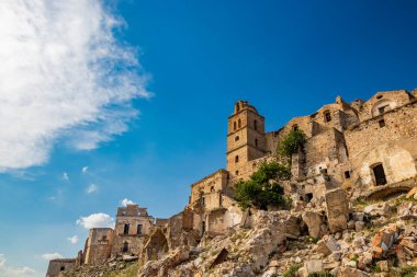 Craco, Basilicata, İtalya. Bir heyelan sonucu hayalet kasaba yok edildi ve terk edildi. Çökmüş evler ve bitkiler tarafından istila edilmiş kalıntılar. Kırık duvarlar, pencereler ve kapılar. Kilisenin çan kulesi.