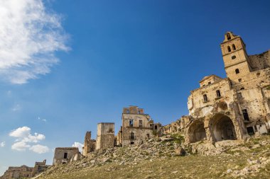 Craco, Basilicata, İtalya. Bir heyelan sonucu hayalet kasaba yok edildi ve terk edildi. Çökmüş evler ve bitkiler tarafından istila edilmiş kalıntılar. Kırık duvarlar, pencereler ve kapılar. Kilisenin çan kulesi.