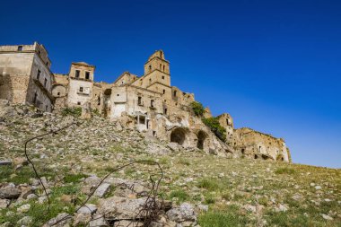Craco, Basilicata, İtalya. Bir heyelan sonucu hayalet kasaba yok edildi ve terk edildi. Çökmüş evler ve bitkiler tarafından istila edilmiş kalıntılar. Kırık duvarlar, pencereler ve kapılar. Kilisenin çan kulesi.