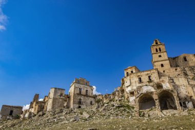 Craco, Basilicata, İtalya. Bir heyelan sonucu hayalet kasaba yok edildi ve terk edildi. Çökmüş evler ve bitkiler tarafından istila edilmiş kalıntılar. Kırık duvarlar, pencereler ve kapılar. Kilisenin çan kulesi.