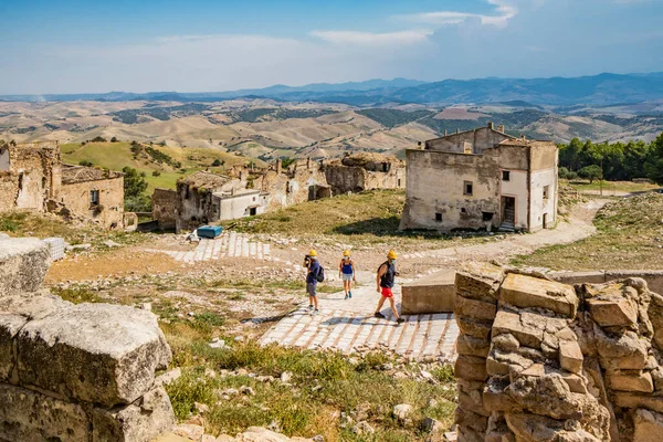 Craco, Basilicata, İtalya. Bir heyelan sonucu hayalet kasaba yok edildi ve terk edildi. Eski köyün kalıntıları ve kalıntıları görünüyor. Koruyucu kask takan bazı turistler kenti ziyaret ediyor
