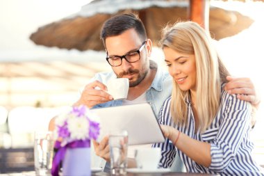 Dijital tablet vasıl onun tarafından oturan bir erkek arıyorum bir kafeterya masada gülümseyen genç kadın