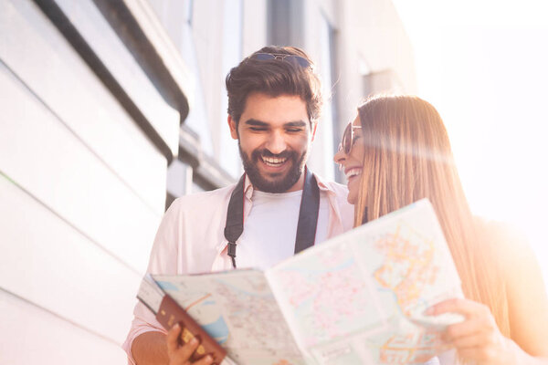 Happy couple with map choosing first destination in sunny Europe city