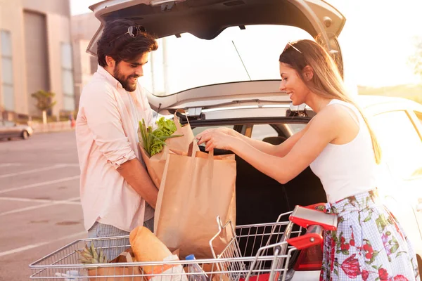 Молодая Счастливая Пара Упаковывает Продукты Багажник Автомобиля Супермаркета — стоковое фото