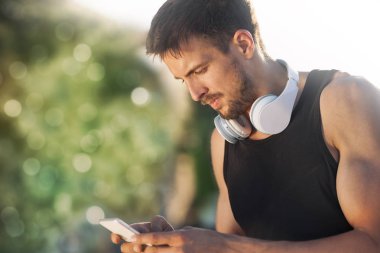 Bir şey mobil akıllı telefonundan yazarak ve gün batımında duran erkek atlet 
