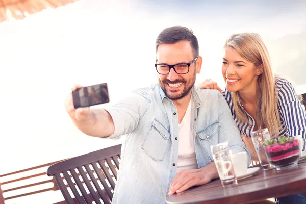 积极可爱的情侣在爱做自拍与智能手机在咖啡店 — 图库照片