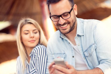 Mutlu adam akıllı telefon kullanarak onların arkadaşları ile sohbet online onun kız arkadaşı ile