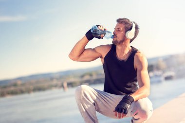 Genç yakışıklı içme suyu eğitimden sonra sert adam. Adam canlandırıcı tatil dışında spor yaptıktan sonra. Açık havada eğlence, germe ve eğitim uygun vücut