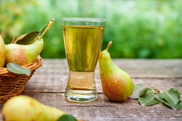 Glass with pear juice and ripe pear on wooden table