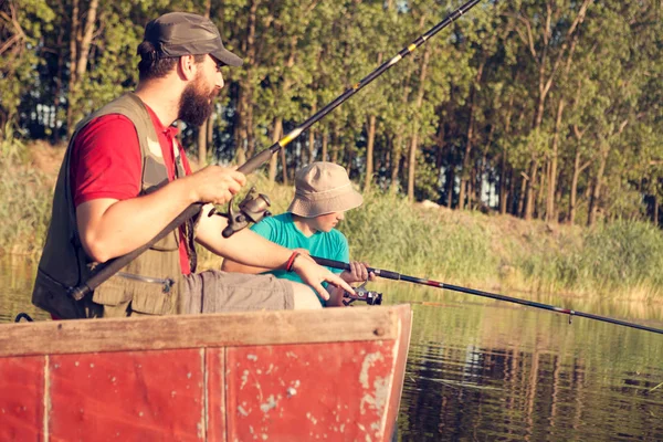 Dad and son fishing at lake in the countryside, they sitting with fishing rods and waiting for catch