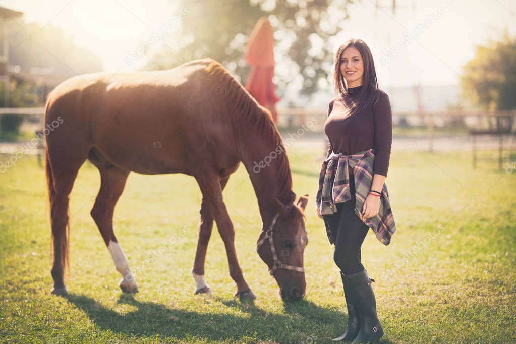 Beautiful young woman with her horse over sunny day