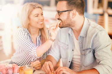 Sabahları kahvaltı sahip çift. Genç kadın sevgilisi kruvasan bir parça ile besleme