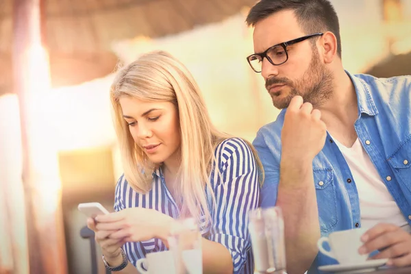 Jealous man looking  in girlfriend phone while she texting  a message, relationship problem