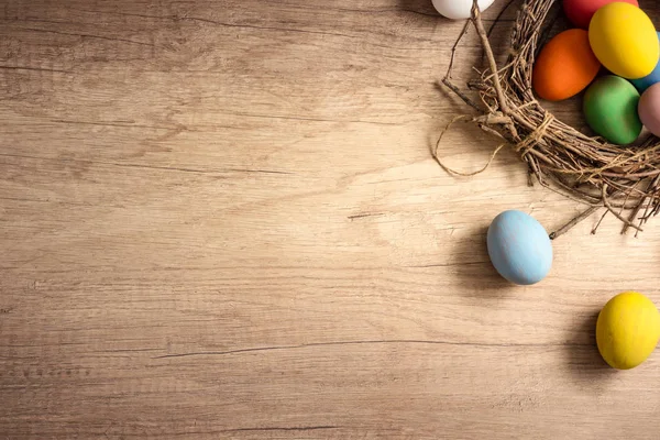 Huevos de Pascua coloridos en nido con flor de tulipán en madera rústica — Foto de Stock