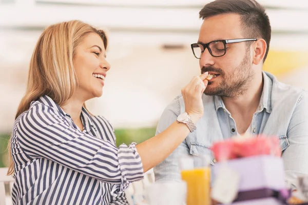 Schönes verliebtes Paar sitzt im Café und isst Croissant — Stockfoto