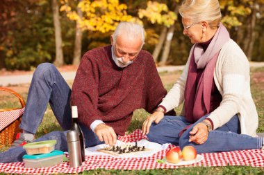 Yaşlı çift çimenlerin üzerinde oturup satranç oynuyor