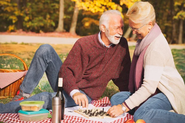 Šťastný starší pár sedící na trávě a baví romantické rande — Stock fotografie