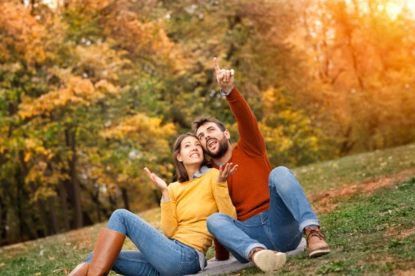 Homem feliz e mulher sentar na grama no parque de outono com espaço de cópia — Fotografia de Stock