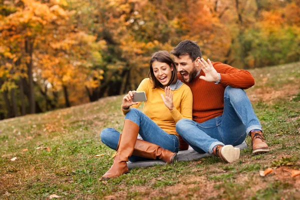 Unga glada par som använder smartphone för att prata med sin fre — Stockfoto