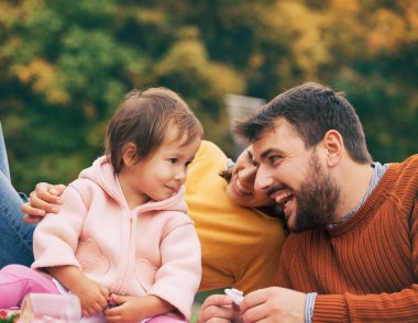 Aile, eğlence ve insan kavramı - mutlu anne, baba ve küçük kızı sonbahar parkta piknik sahip.
