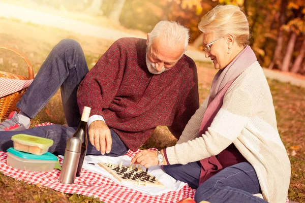 Šťastný starší pár relaxační v parku hrát šachy — Stock fotografie